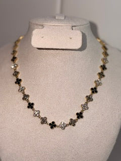 A gold and black beaded necklace displayed on a beige fabric jewelry bust.