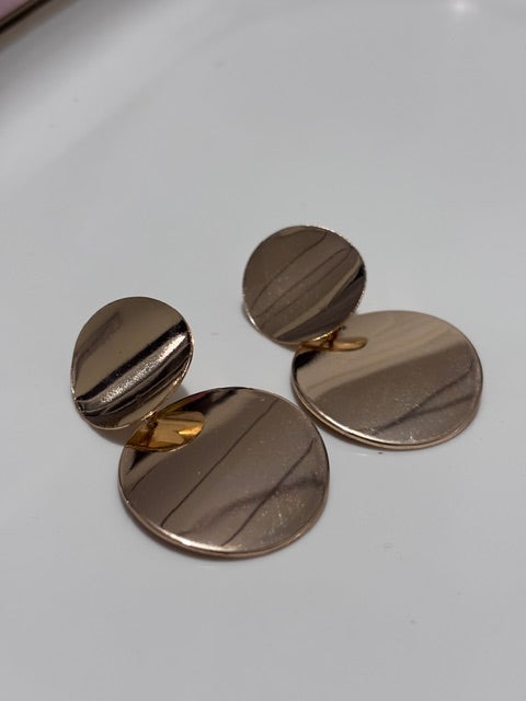 Set of gold circular cufflinks style earrings on a light gray background