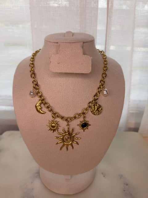 Gold necklace with sun and moon charms on a mannequin bust.