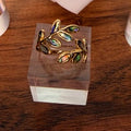 Gold ring with colorful stones on a wooden stand