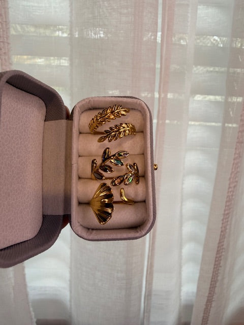Gold earrings in an open jewelry box with a soft pink interior.