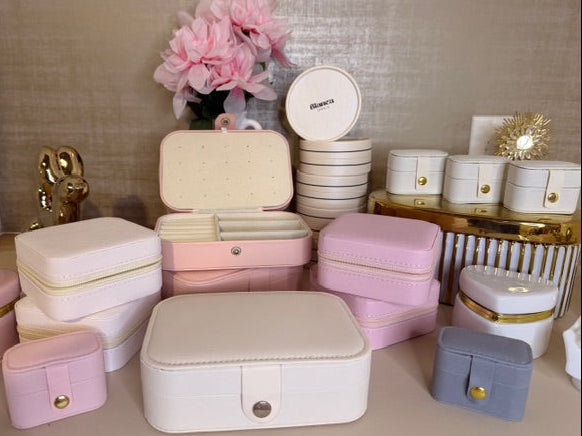 Collection of jewelry boxes in various colors on a table with decorative items in the background.
