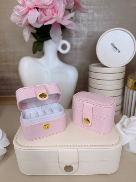 Pink jewelry box with a white vase and pink flowers on a textured surface