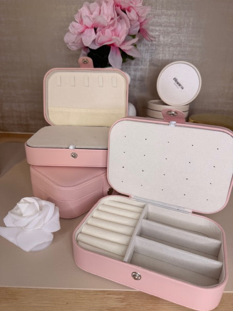 Pink jewelry box with jewelry on a wooden surface