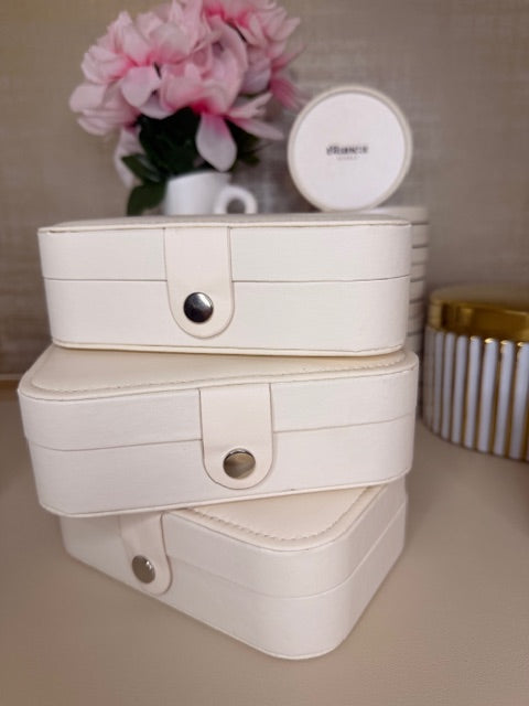 Stacked White leather jewelry box with a small round box on a beige surface