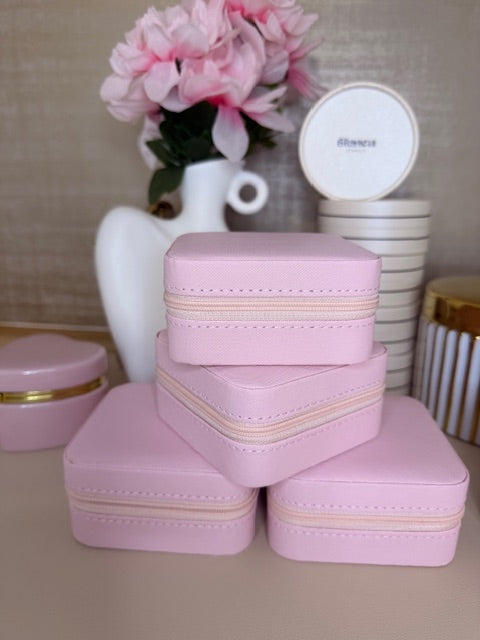 Pink jewelry box with gold accents on a neutral background