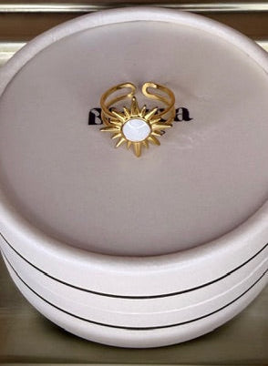 Gold ring with a star design on a white round box.