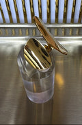 gold geometric open ring on a clear stand and on a metallic surface
