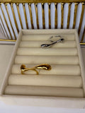 Gold rings displayed on a beige ring stand with a white and gold background.