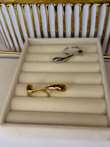 Gold rings displayed on a beige ring stand with a white and gold background.