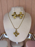 Gold earrings with floral design and matching necklace on a white bust against a pink background
