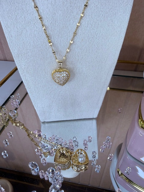Gold necklace with heart-shaped pendant on a light gray surface