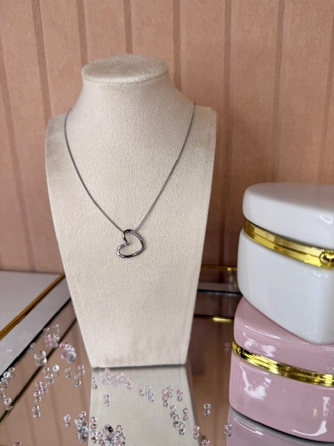 Necklace with hollow heart shape pendant on a mannequin with jewelry display in the background