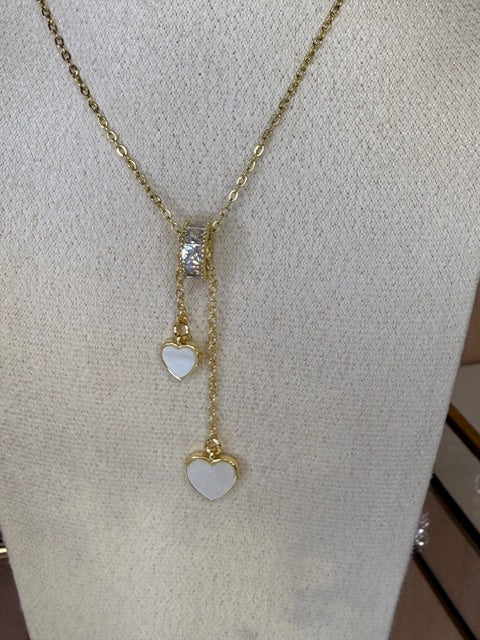 Gold necklace with heart-shaped pendants on a light gray surface