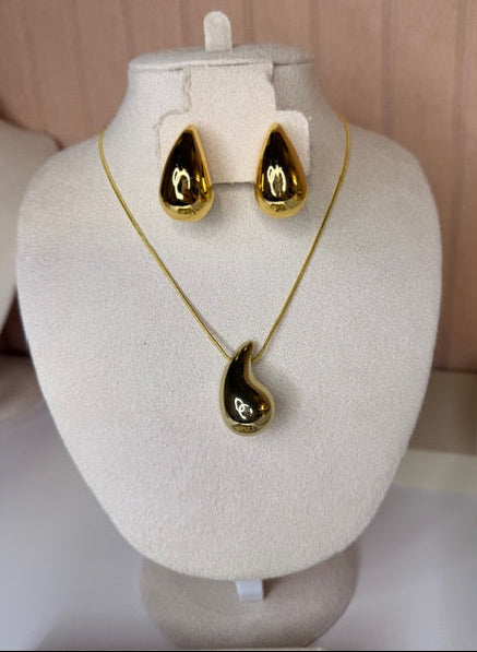 Gold water drop design pendant necklace and earrings set on a white mannequin bust.