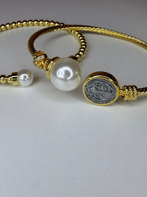 Two Gold rope style bracelets with pearls and a coin charm on a light gray background