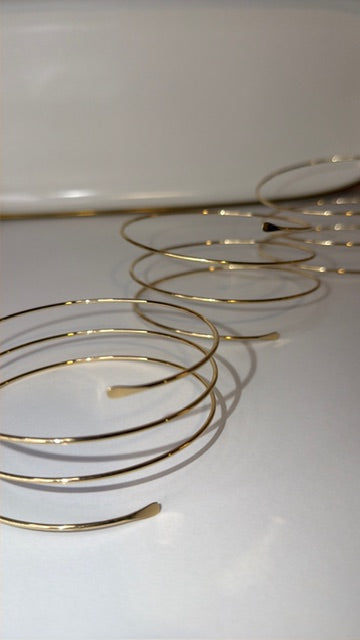 Gold arm bracelets on a white surface