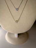 a gold and silver necklace with a stone center on a beige display stand