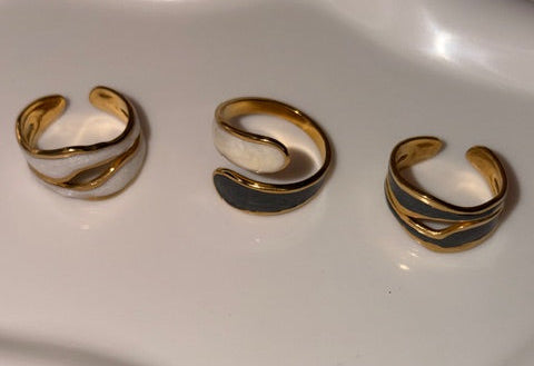 Three gold and black rings on a white surface