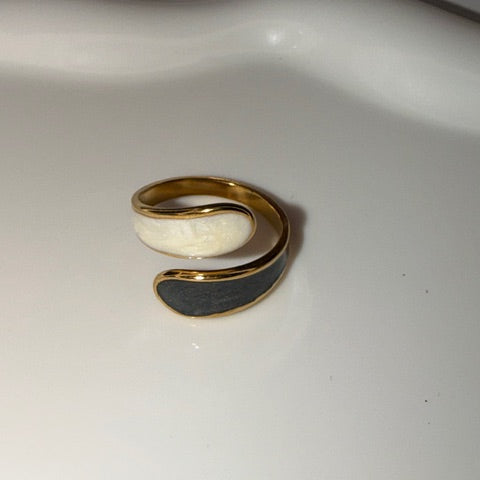 Gold black and white ring on a white surface