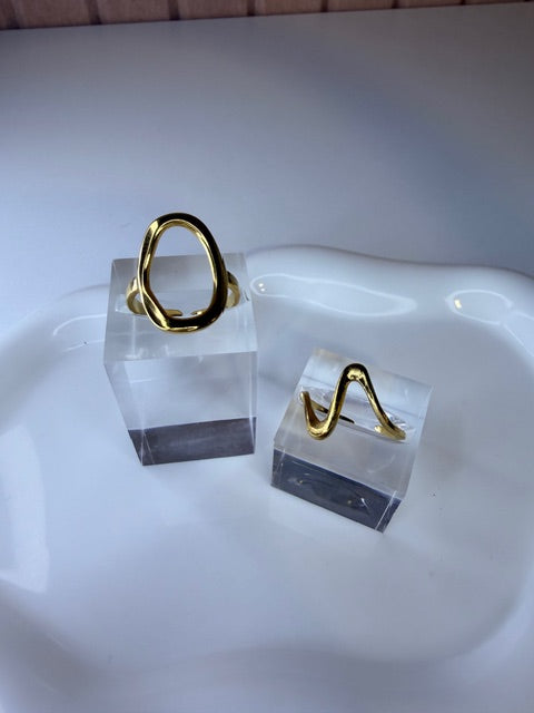 Gold rings on a white stand with a neutral background