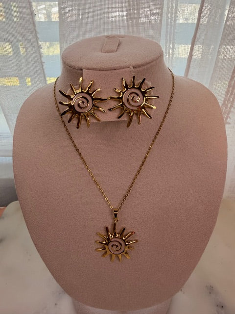 Gold sun-shaped necklace and earring set on a mannequin bust with a blurred window background