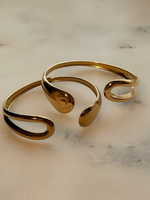 Open Gold bracelet on a marble surface