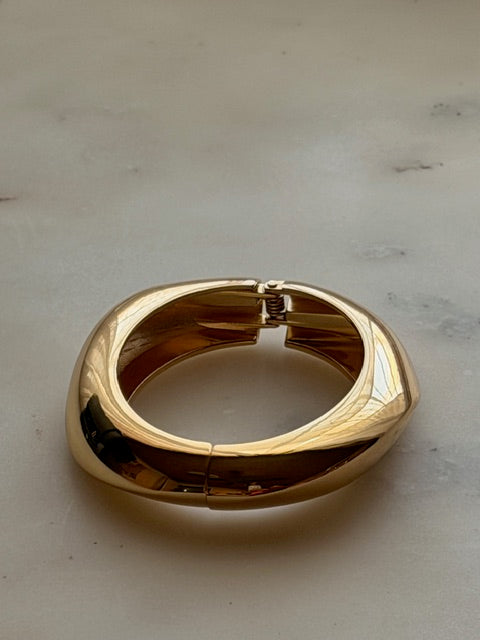 Gold bracelet on a light gray surface