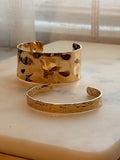 Two Gold bracelets on a marble surface with a soft focus background
