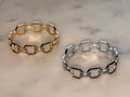 Gold and silver chain-link bracelets on a light marble surface
