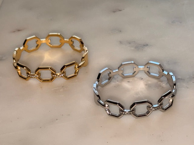 Gold and silver chain-link bracelets on a light marble surface