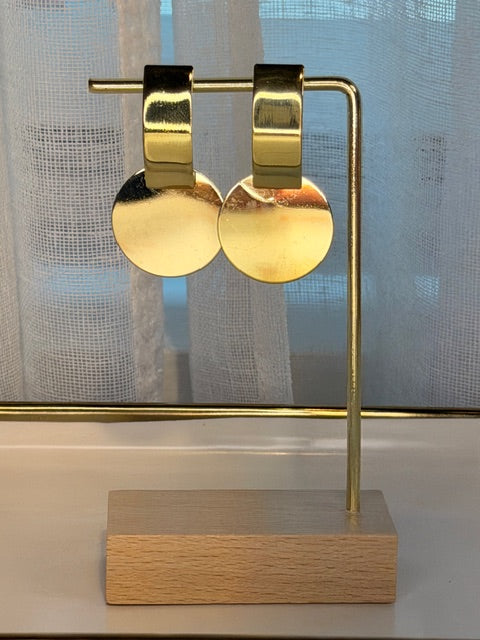 Gold geometric earrings hanging on a  gold stand with wooden frame