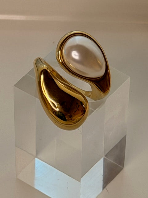 Gold ring with a pearl on a geometric patterned surface