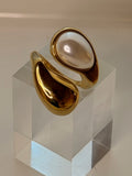 Gold ring with a pearl on a geometric patterned surface
