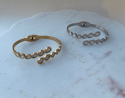Gold and silver spring open bracelets on a marble surface