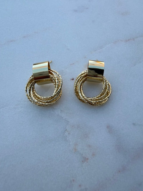 Pair of gold hoop earrings on a light blue marble surface