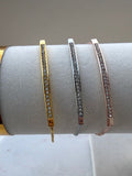 Three bracelets on a white cylindrical stand with a plain background