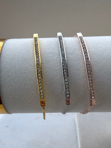 Three bracelets on a white cylindrical stand with a plain background