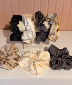 Set of black, gold, and beige hair scrunchies on a white background