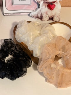 Set of hair accessories including scrunchies and a small box on a wooden surface.