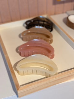 Set of four hair clips in different colors on a wooden tray.