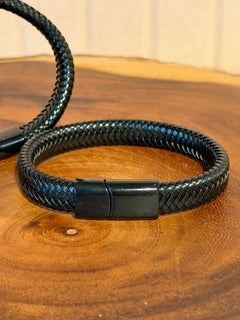 Black braided cord with a metallic clasp on a wooden surface
