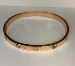 Rose gold bracelet with engraved cross design and zircons on a white background