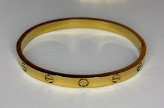 Gold bracelet with engraved design on a white background