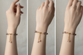 Three-panel close-up of a person's wrist wearing a delicate beaded bracelet with dangling pearl-like charms. The bracelet features small gold-toned beads, pink and brown beads, and two dangling pearl clusters.