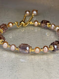 Close-up of a beaded bracelet with pearls and gold accents on a textured surface