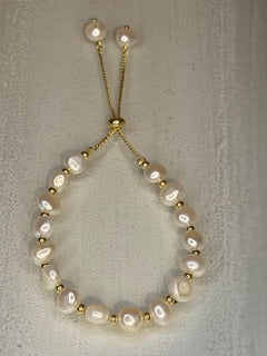 Pearl bracelet with gold accents on a light gray background