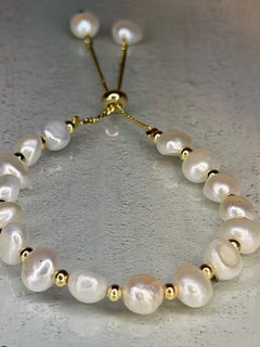 Pearl bracelet with gold accents on a light gray background
