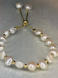 Pearl bracelet with gold accents on a light gray background