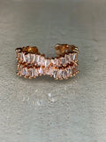 Rose gold ring with clear gemstones on a gray background
